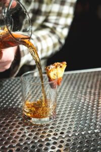 Golden liquid being poured into a glass tumbler at the Tough Luck Club