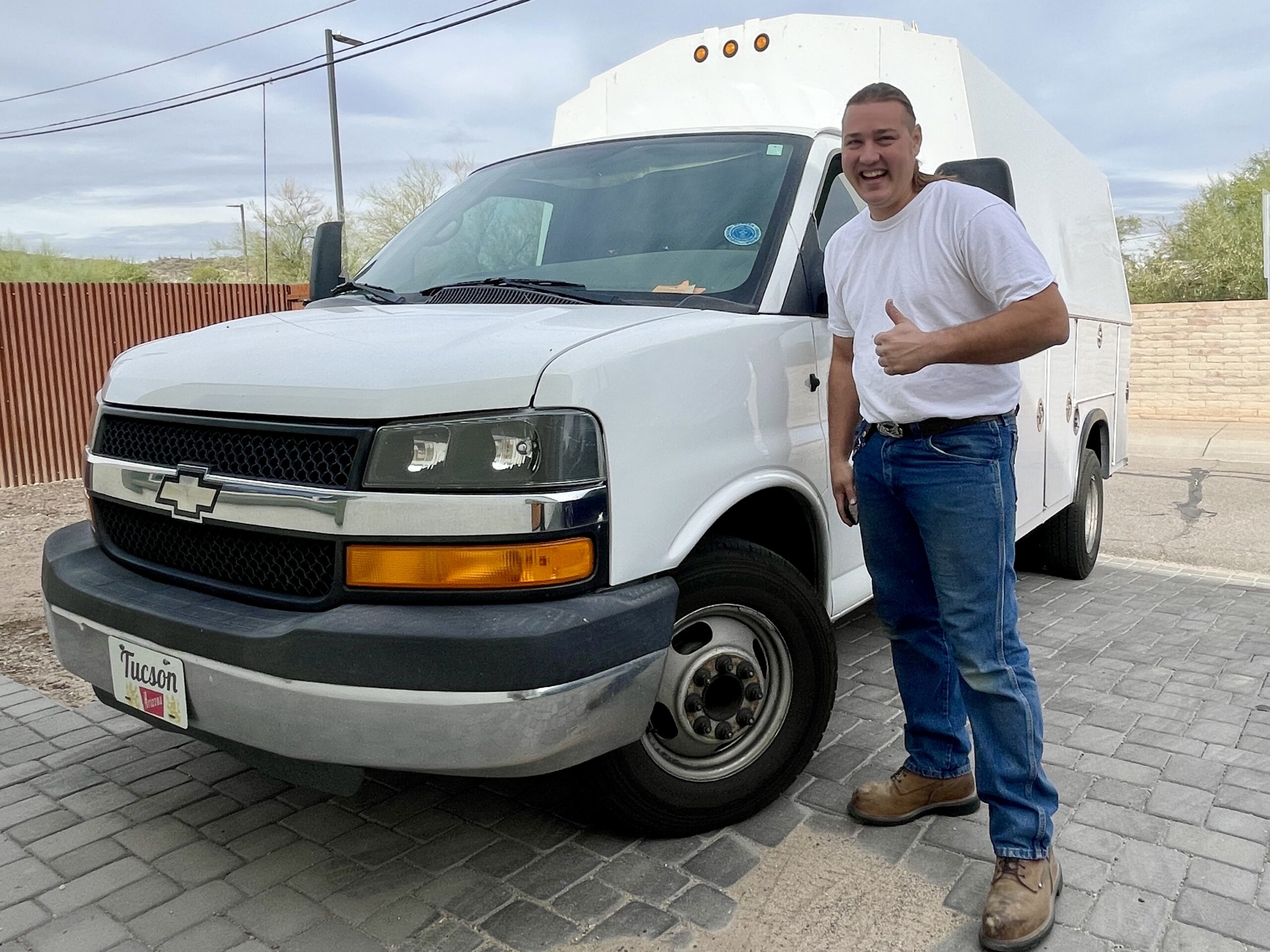 Matt Gruendler, owner of Genius Plumbing, smiling and giving a thumbs-up in front of his service truck.