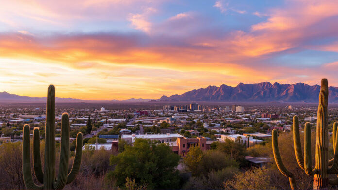 Aerial view of Tucson, Arizona at sunset with the Santa Catalina Mountains and saguaro cacti in the foreground.